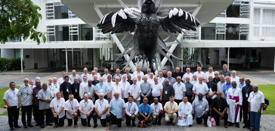 Large group of men standing in front of  sculpture in Fiji